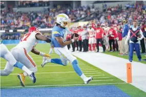  ?? AP Photo/Marcio Jose Sanchez ?? ■ Los Angeles Chargers quarterbac­k Justin Herbert scores a touchdown as Kansas City Chiefs linebacker Darius Harris defends during the first half of an NFL football game Dec. 16 in Inglewood, Calif.