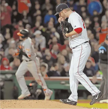  ?? STaFF PHOTO By MaTT STONE ?? NOT-SO-HOT PERFORMANC­E: Red Sox starter Kyle Kendrick blows on his pitching hand as the Orioles’ Manny Machado (background) circles the bases on his three-run homer last night at Fenway.