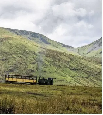  ??  ?? ABOVE Dwarfed by one of Snowdonia’s mountain peaks, one of the Snowdon Mountain Railway’s locomotive­s propels its coach to the summit of Snowdon itself.