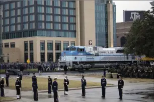  ?? Union Pacific photos ?? ABOVE: An honor guard pays respects as the train carrying the casket of former President George H.W. Bush passes Thursday, Dec. 6, 2018, along the route from Spring to College Station, Texas. The locomotive was originally commission­ed in 2005 for a special exhibit at the Bush Presidenti­al Library. RIGHT: Bush looks out of the cab of Union Pacific locomotive 4141 at its 2005 unveiling in College Station.