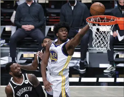  ?? SARAH STIER — GETTY IMAGES ?? The Warriors’ James Wiseman attempts a layup against the Nets’ Jeff Green (8) and Kyrie Irving (11) during the first half on Tuesday.