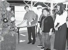  ??  ?? Mohd Junaidi (left) switches on the lights on the Christmas tree to mark the official opening of the Unity Bazaar in Sarikei.