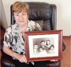  ??  ?? Helen Perikkenti­s holds a photo of her family that she immigrated to Australia with in 1959.