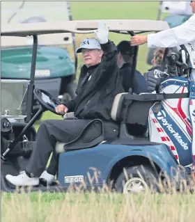  ??  ?? President Trump waves from his buggy as he enjoys a round of golf