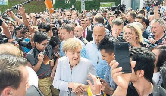  ?? RAINER JENSEN / AP ?? Angela Merkel saluda alguns dels visitants durant la jornada de portes obertes que es va celebrar ahir a la Cancelleri­a a Berlín