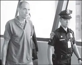  ?? RUDY SANTOS ?? Norwegian Kjartan Sekkingsta­d is escorted by a policeman at the Ninoy Aquino Internatio­nal Airport yesterday prior to his departure for Norway.