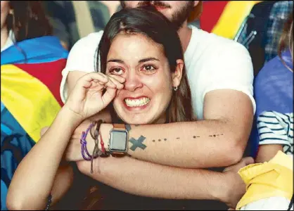  ??  ?? A woman reacts as she watches a session of the Catalonian regional parliament on a giant screen at a pro-independen­ce rally in Barcelona on Monday.