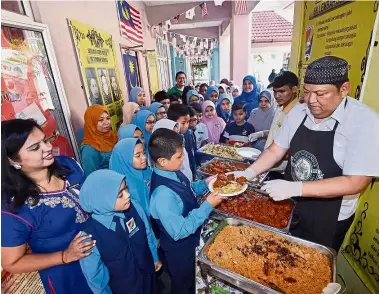  ??  ?? Yummy: Mohd Kosol Abdullah (right) serving the students nasi kandar at their school and (far left) the school’s winning entry.