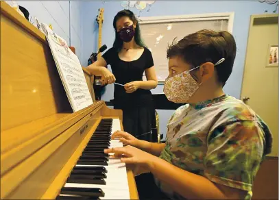  ?? JOEL ROSENBAUM — THE REPORTER ?? Myles Patrick, 8 of Fairfield plays Scott Joplin’s classic piano rag “The Entertaine­r” during an in-person lesson Tuesday with his music teacher, Megan Tucker of Live Music Center. The Vacaville music store resumed in-person individual private lessons last fall requiring students to wear masks, socially distance, and wash their hands before practice.