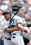  ?? Associated Press ?? n New York Yankees first base coach Tony Pena, left, restrains catcher Austin Romine after he was ejected from the game after fighting with Detroit Tigers’ Miguel Cabrera on Thursday in Detroit.