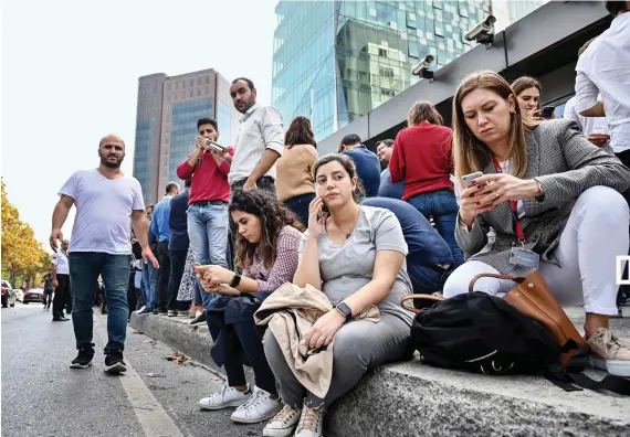  ?? AFP ?? Office workers speak on their phones after fleeing their buildings in the Maslak District of Istanbul on Thursday, after an earthquake struck the city of 15 million at 1:59 p.m.