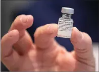  ?? Associated Press ?? ■ University of Texas School of Nursing faculty member Kari McDonald holds a vial of the Pfizer-BioNTech COVID-19 vaccine Tuesday at the University of Texas Health Austin Dell Medical School in Austin.