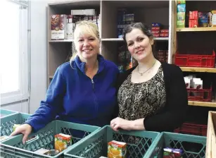  ??  ?? Terri and Kendra at the Food Bank are in need of some supplies to continue filling the monthly food hampers, as you can see the Kraft Dinner shelf behind them is looking empty.