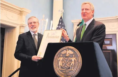  ??  ?? Green day: New York Mayor Bill de Blasio hands former Sinn Fein president Gerry Adams a proclamati­on renaming St Patrick’s Day ‘Gerry Adams Day’