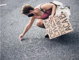  ??  ?? Fiona McElroy, who went to Trinity College, draws“Justice for Breonna”in chalk during the protest, which was organized by Black Lives Matter 860.