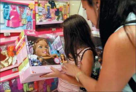  ?? THE ASSOCIATED PRESS ?? Katherine Gallagher of Glen Rock, N.J., shows her mother Emily a “Primp and Polish” Barbie on July 19, 2004, at Toys R Us flagship Times Square store in New York. Toys R Us CEO David Brandon told employees Wednesday that the company’s plan is to...