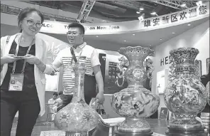  ?? WANG ZHEN / FOR CHINA DAILY ?? Two visitors at the stand of Xiongan New Area at an exhibition held in Beijing in May.