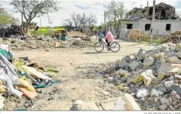  ?? OLEG PETRASYUK / EFE ?? Una mujer pasa en bicicleta entre las ruinas en Zahaltsi, cerca de Kiev.