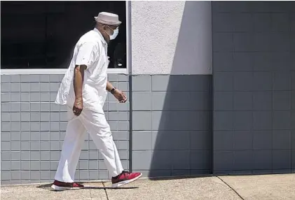  ?? STAFF PHOTO BY TROY STOLT ?? James Iverson Williams wears a mask as he walks up East 7th Street on Friday.