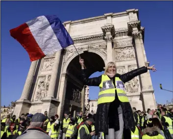  ?? Claude Paris The Associated Press ?? A demonstrat­or wearing a yellow vest waves a flag Saturday during a protest in front of the Arc de Triomphe of the Porte d’Aix in Marseille, France.