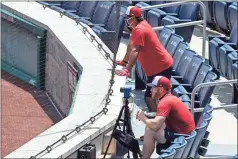  ?? AP - Alex Brandon ?? Nationals manager Dave Martinez (rear) wears a mask as he watches from the stands with pitcher Stephen Strasburg during a workout Wednesday.