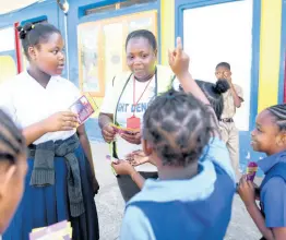  ?? CHIEF PHOTO EDITOR RICARDO MAKYN/ ?? Jennifer Josephs, a temporary vector-control worker, handing out pamphlets to students of Friendship Primary School during a dengue clean-up exercise at the St Catherine school yesterday.