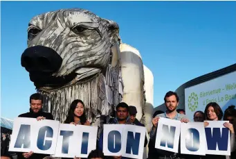  ??  ?? Greenpeace activists hold signs reading ‘Action Now’ in front of Greenpeace’s giant puppet polar bear Aurora during a protest at the climate change conference in Paris yesterday. Photo: Getty