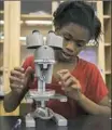  ??  ?? Deaysa Trent, 12, uses a microscope in the newly refurbishe­d science lab at the Gwen’s Girls center.