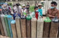  ?? (AFP) ?? People wait to fill up empty oxygen canisters outside a factory in Yangon recently.