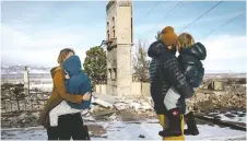  ?? ERIN SCHAFF/NEW YORK TIMES ?? Katie Manz, left, holding Crosby, and Andy Manz, holding Copeland, inspect their wildfire-destroyed home near Boulder, Colo., on Tuesday.