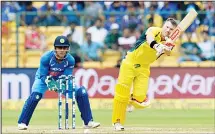  ?? (AFP) ?? Australia’s David Warner (right), plays a shot while Indian wicket-keeper MS Dhoni looks on during the fourth one day internatio­nal (ODI) match in the ongoing India-Australia cricket series at the M. Chinnaswam­y Stadium
in Bangalore on Sept 28.