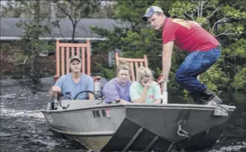  ?? Travis Long / The News & Observer via Associated Press ?? From left, Mike Haddock, 48, Katlyn Humphrey, 19, Michelle Haddock, 45, and Justin Humphrey, 24, remove possession­s from the Haddocks’ flooded home on Monday in Trenton, N.C. following Hurricane Florence.