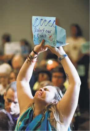  ?? James Tensuan / Special to The Chronicle ?? Genoa Robertson shows her support for Charles Lester as he addresses the Coastal Commission meeting in Morro Bay.