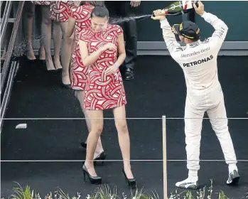  ?? / CARLOS BARRIA / REUTERS ?? Mercedes Formula One driver Lewis Hamilton of Britain sprays champagne at a grid girl as he celebrates his victory at the Chinese Grand Prix at the Shanghai Internatio­nal Circuit in in this file picture.