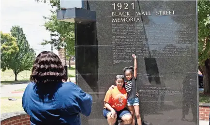  ??  ?? Madre e hija se toman una foto frente a un monumento recordator­io del Wall Street Negro de Tulsa