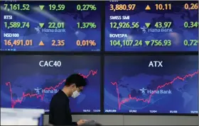  ?? (AP/Lee Jin-man) ?? A currency trader walks past screens Thursday at a foreign exchange dealing room in Seoul, South Korea. Asian markets had a mixed day.