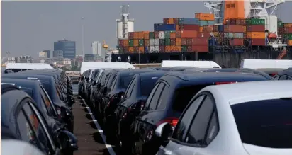  ?? (Reuters) ?? Cars are lined up past a container vessel at the port in Valencia, Spain recently.