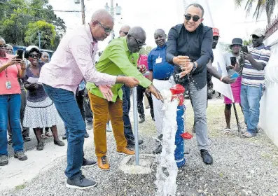  ?? CONTRIBUTE­D ?? Local Government Minister Desmond McKenzie (centre) flanked by Norman Scott (right), chairman of the St Catherine Municipal Corporatio­n, and Dr Christophe­r Tufton, member of parliament for St Catherine West Central, when they turned on the water in Watermount in March of last year.