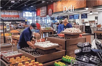  ??  ?? Finishing touches are added and shelves are stocked Monday for Wednesday’s opening of a Homeland grocery store in Oklahoma City’s eastside neighborho­od, which has been classified as a “food desert.”