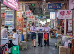  ?? ?? Bank staff explain supporting policies to self-employed individual­s and small business owners at a wholesale market in Jiangbei District, Chongqing, on August 1