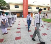  ?? AP, Reuters ?? ■ Students wearing face masks as they walk to their classrooms at a school in Karachi yesterday. Officials welcomed millions of children back to school following educationa­l institutio­ns reopened in the country amid a steady decline in coronaviru­s deaths and infections.