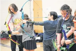  ?? JASON MALLOY PHOTOS ?? Levi Marchand, second from right, trains his eye on the target during archery practice recently in Coldbrook.