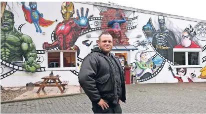  ?? NGZ-FOTO: ANJA TINTER ?? Thomas Panzer steht vor seinen Kunstwerke­n: An den Wänden des Unternehme­ns „Grobi.tv“durfte er sich austoben. Das Ergebnis kann sich absolut sehen lassen.
