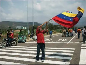  ?? AP/RODRIGO ABD ?? A supporter of the Venezuelan government waves a national flag Friday as people begin arriving for the three-day Hands Off Venezuela music festival at the Tienditas Internatio­nal Bridge on the border with Colombia.