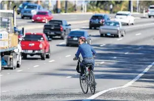  ?? JACOB LANGSTON/STAFF PHOTOGRAPH­ER ?? A bicyclist starts the daunting task of crossing State Road 436, near Essex Avenue, in Altamonte Springs. Seminole County hopes to help cyclists with wider sidewalks and bike-only lanes on major roadways.