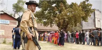  ??  ?? IMPHAL: Indian security personnel stand guard as Manipuris stand in a queue to cast their votes in state assembly elections at a polling station in Sekmai, outskirt of Imphal yesterday. — AFP