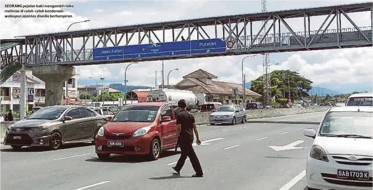  ?? FOTO ?? SEORANG pejalan kaki mengambil risiko melintas di celah-celah kenderaan walaupun jejantas disedia berhampira­n.