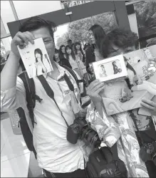  ??  ?? Fans Chen Xiao (left) and Su Liang show photos and posters of their idol Yaorenmao that they bought during the competitio­n in Hangzhou.