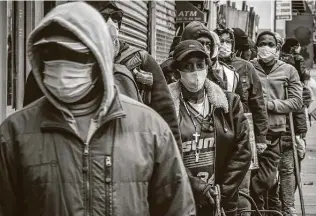  ??  ?? People wait for a distributi­on of masks and food from the Rev. Al Sharpton on April 18 in the Harlem neighborho­od of New York.