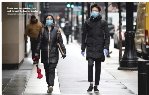  ?? ASHLEE REZIN GARCIA/SUN-TIMES ?? People wear face masks as they walk through the Loop on Monday.